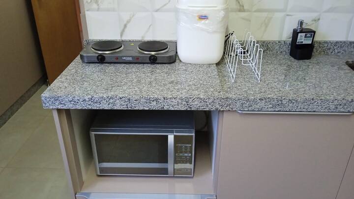 Cooktop elétrico portátil e micro-ondas na bancada de granito