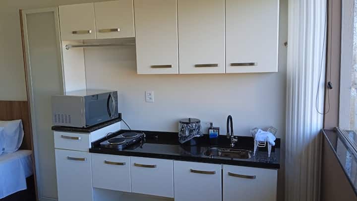 Cozinha linear com armários brancos e bancada preta